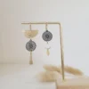 boucles d’oreilles asymétriques dorées avec détail floral et feuille