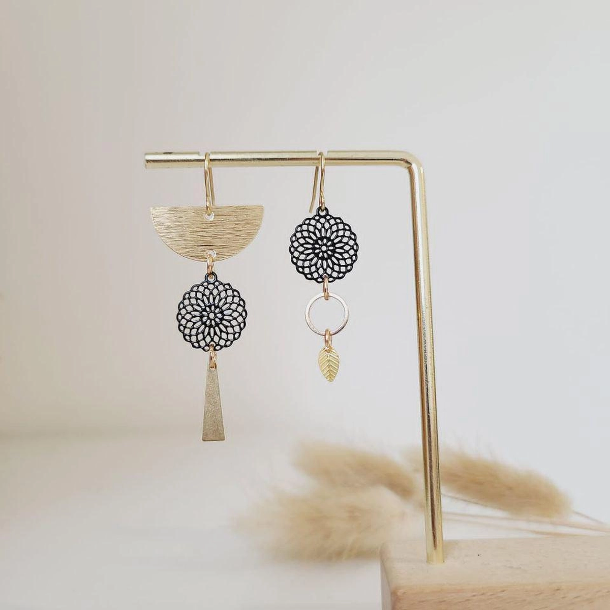 boucles d’oreilles asymétriques dorées avec détail floral et feuille