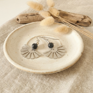 Sans titre (3000 x 3000 px) (33) photo de boucles d'oreilles pendantes forme éventail argenté avec perle noire sur rondin de bois