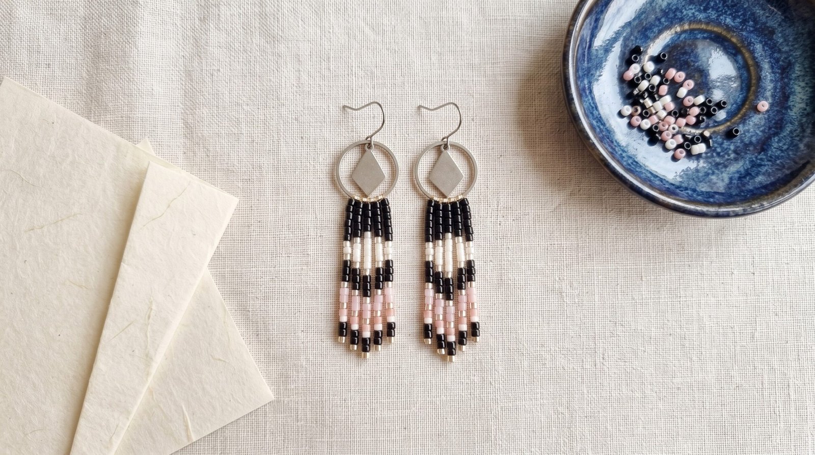 L'origine des perles Miyuki : créoles tissées en perles Miyuki noir, blanc et rose, avec coupelle japonaise de perles de verre