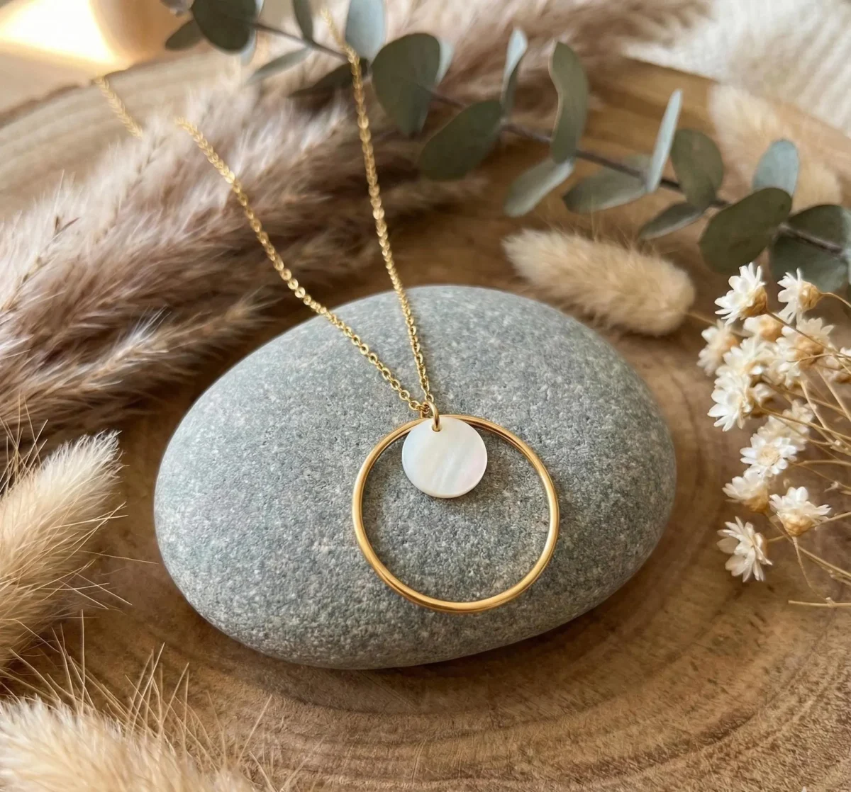 Collier cercle nacré doré posé sur galet avec eucalyptus