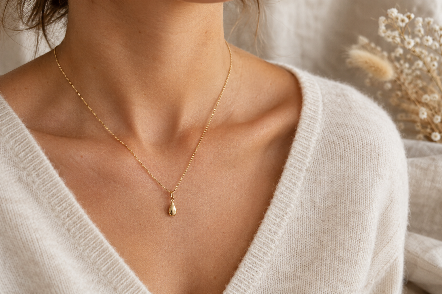 Collier pendentif doré porté avec un col en V