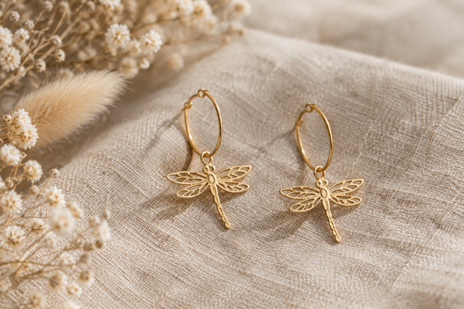 Boucles d’oreilles libellule dorées posées sur du lin