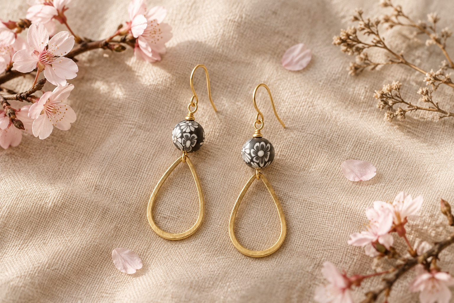 Boucles d’oreilles fleur de sakura dorées posées sur du lin