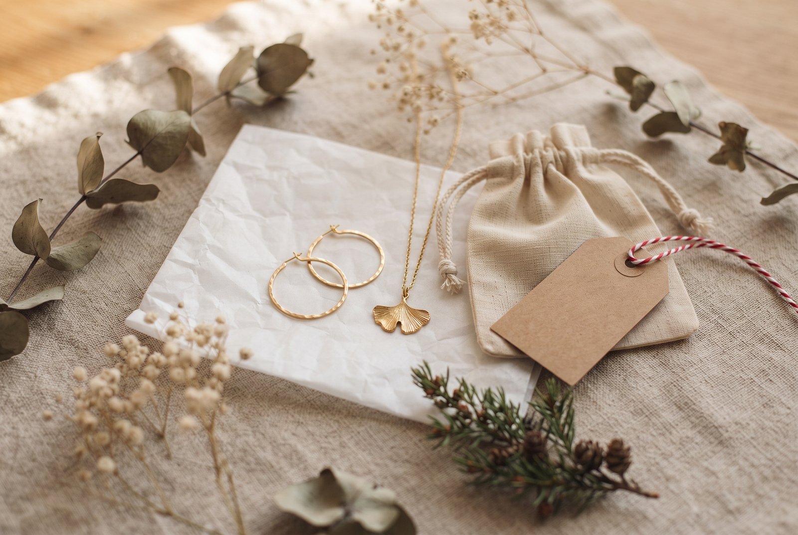 Créoles dorées et collier ginkgo dans leur pochette, prêts à offrir pour Noël