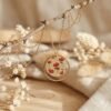 Collier de la parure coquelicot : médaillon doré pailleté à coquelicots rouges dans un cercle doré