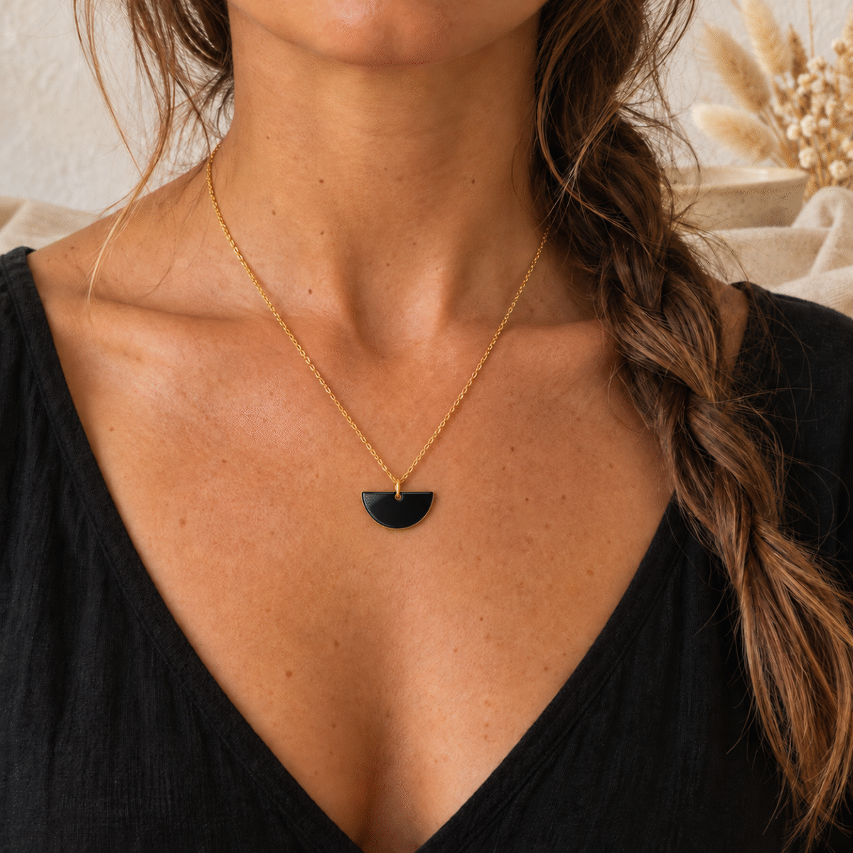 Collier demi-lune noire porté, chaîne dorée fine